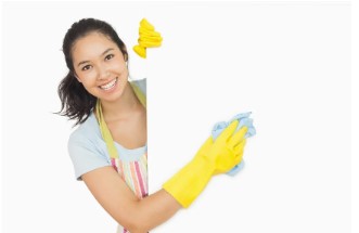 Cheerful-woman-cleaning-white-surface-in-apron-and-rubber-gloves