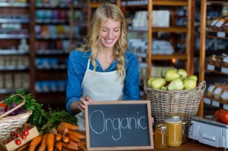 Female-staff-holding-organic-sign-board-in-supermarket-1